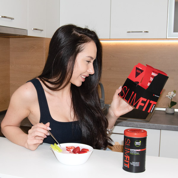 Frau in der Küche mit Schüssel Beeren und SuperFruit Dose